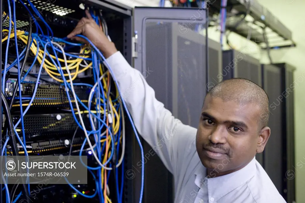 Portrait of a technician connecting computer cables on a network server