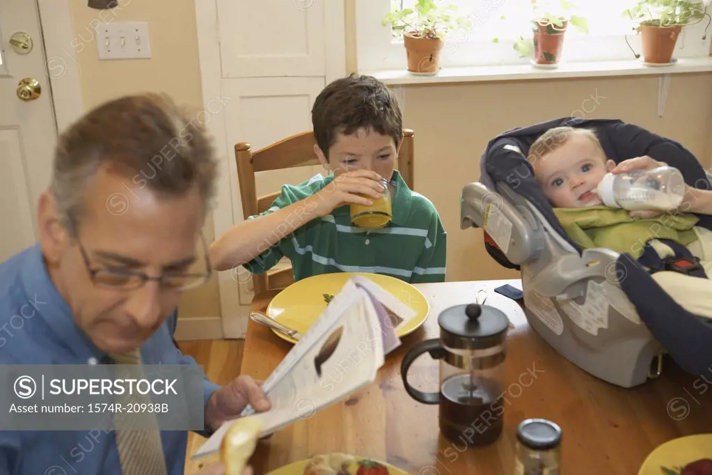 High angle view of a mid adult man with his two sons sitting at a dining table