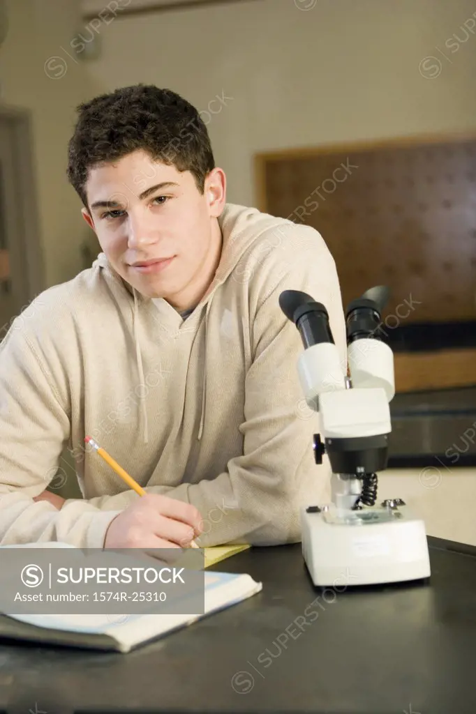 Student sitting by a microscope in a science lab