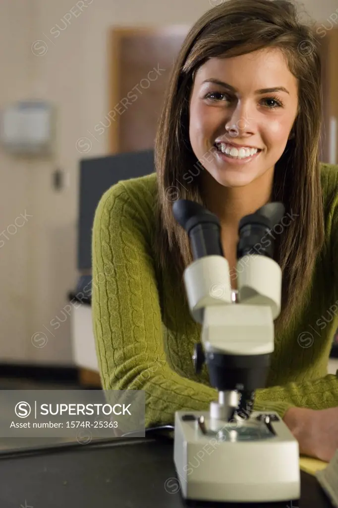 Portrait of a student sitting in front of a microscope in a sciene lab