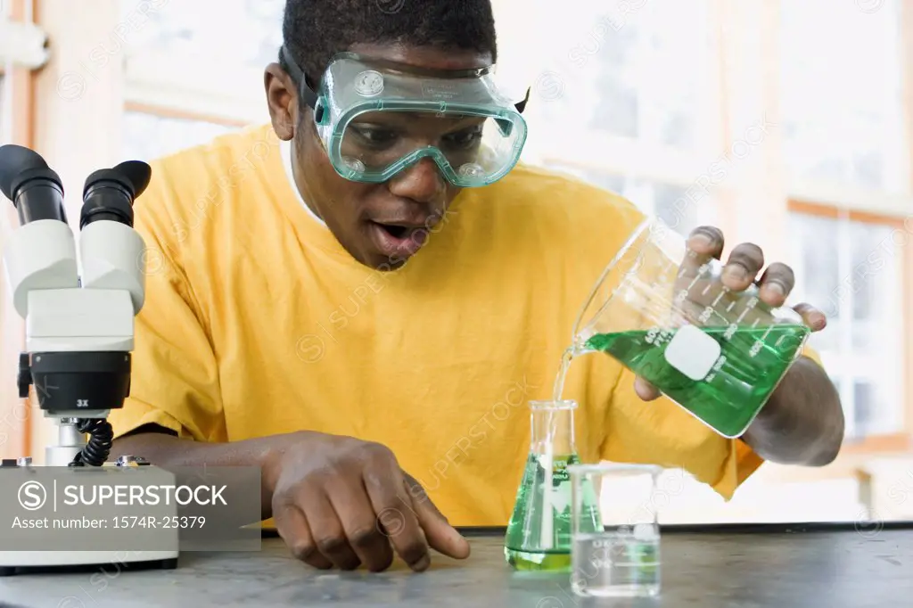 Student pouring liquid in to a beaker in a science lab