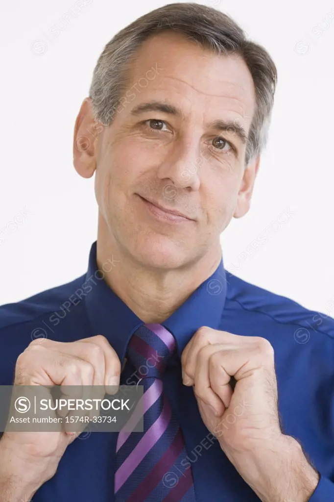 Portrait of a businessman adjusting his tie and smirking