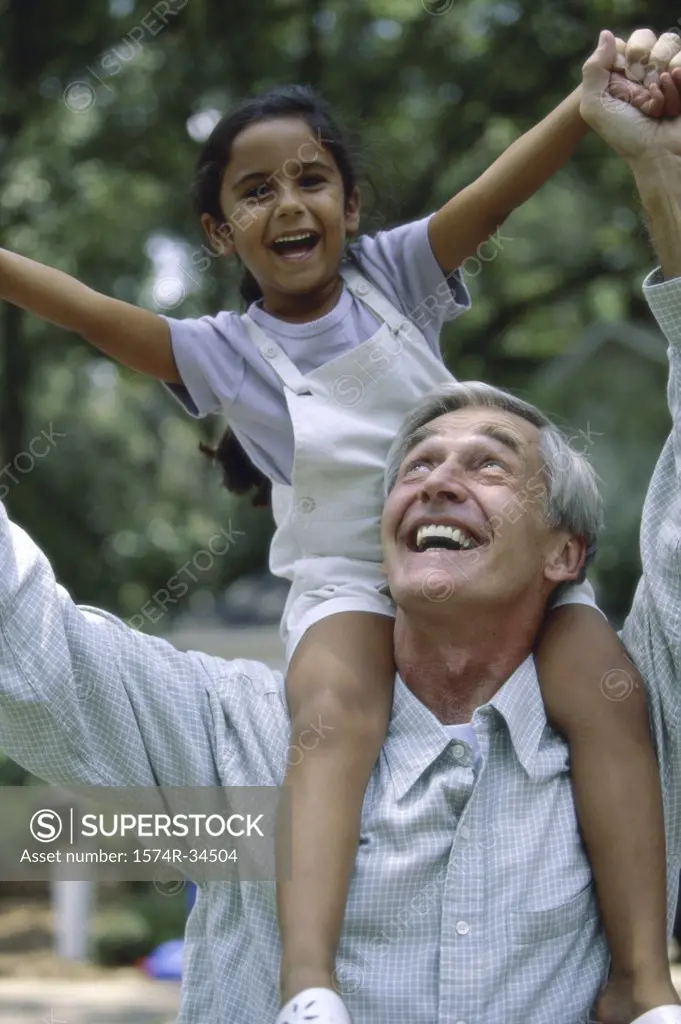 Grandfather carrying his granddaughter on his shoulders