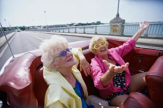 Two senior women traveling together in a convertible car