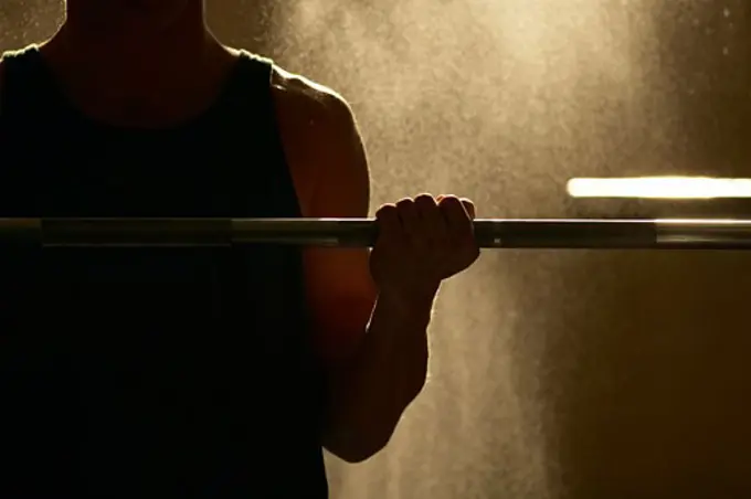 Mid section view of a man exercising with a barbell