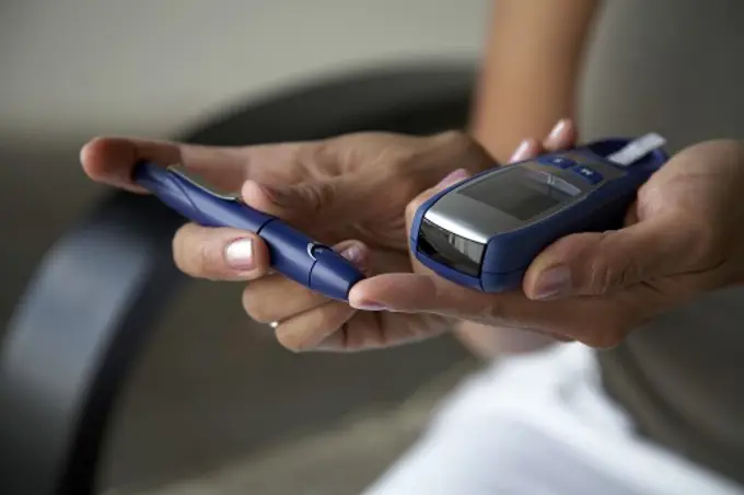 Close-up of a woman taking a blood sample from her finger with a glaucometer