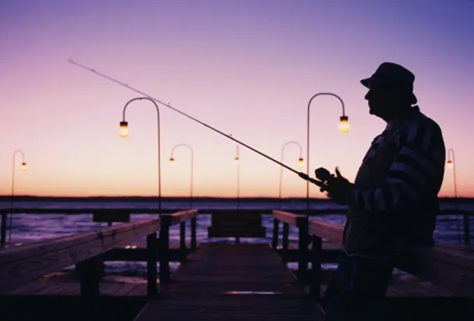 Mature man fishing on a dock in the morning