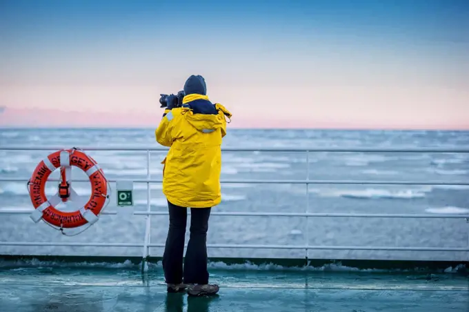 Tourist taking a picture from the deck of the Akademik Sergey Vavilov, Greenland