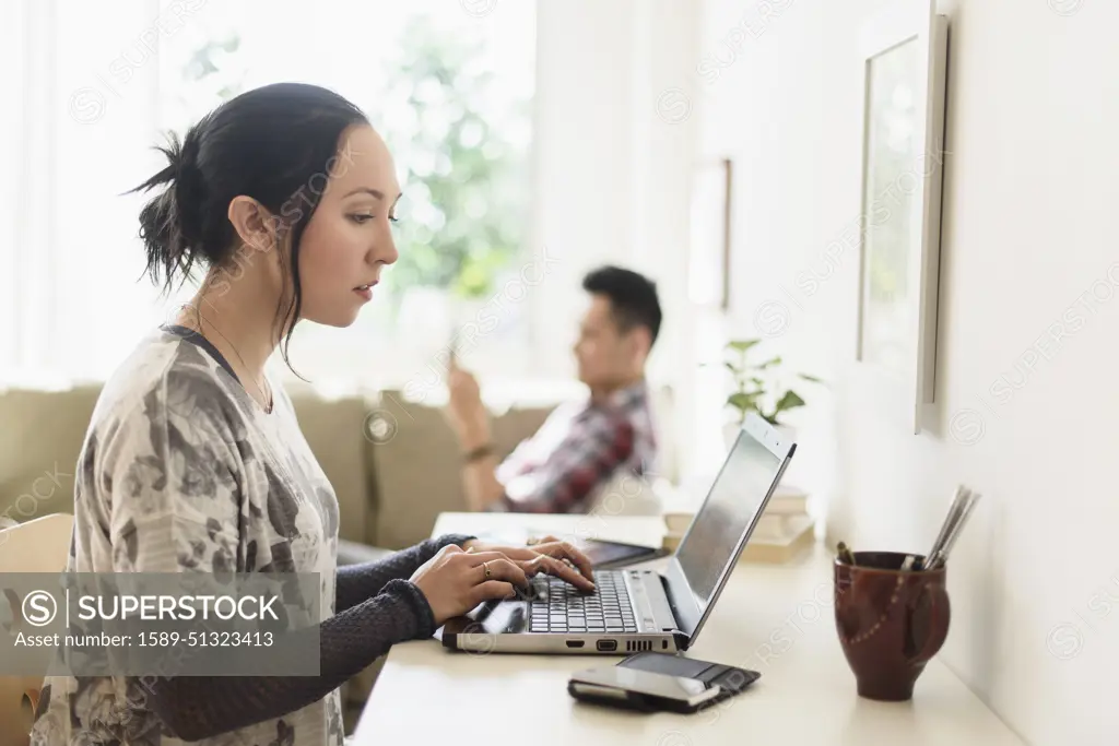 Woman using laptop at desk in living room