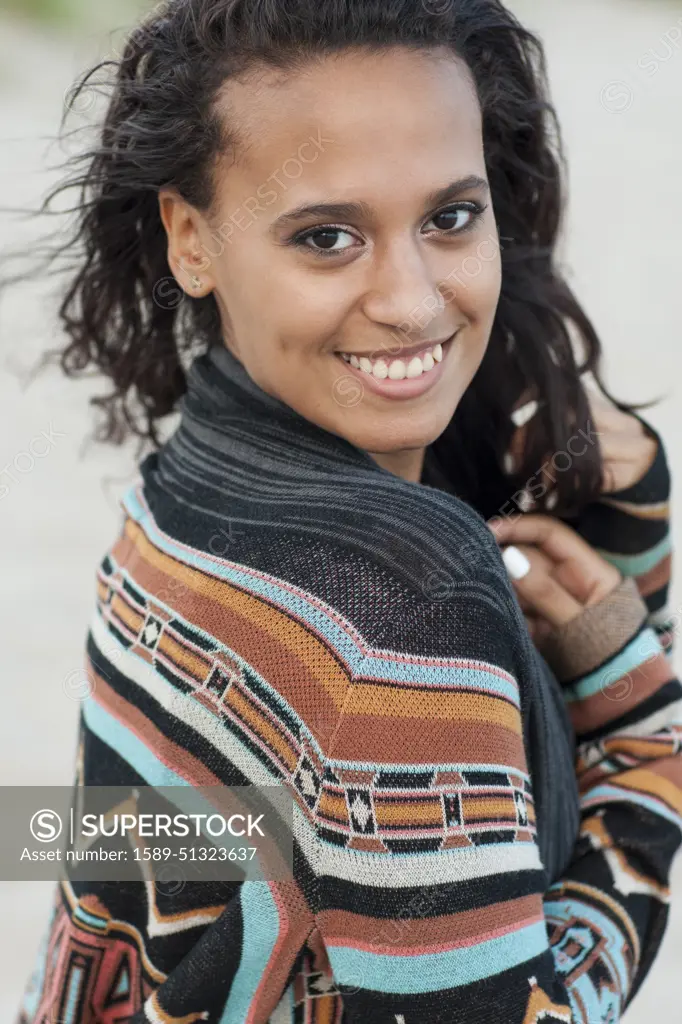 Mixed race woman wearing stylish sweater on beach