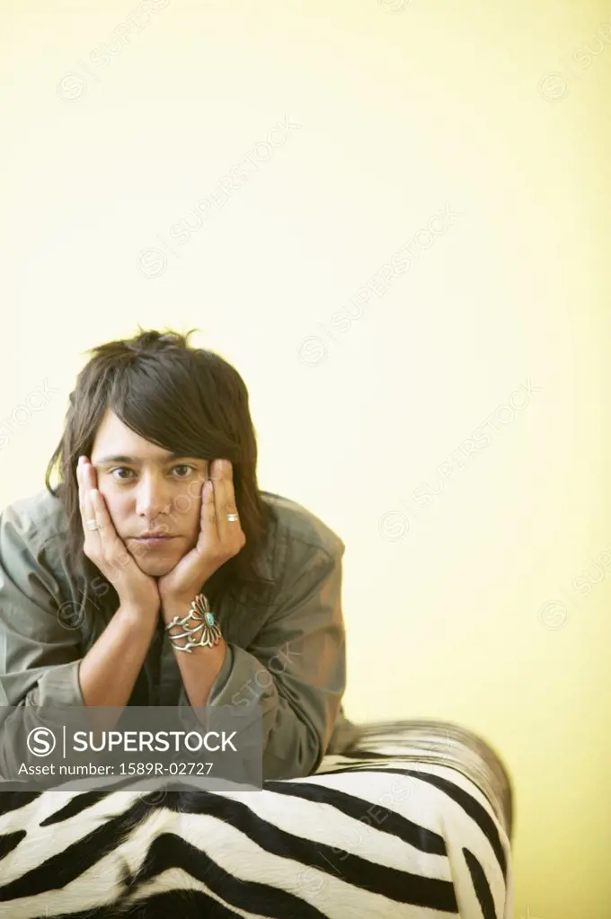 Portrait of a young man lying on a bed with his hands on his cheeks