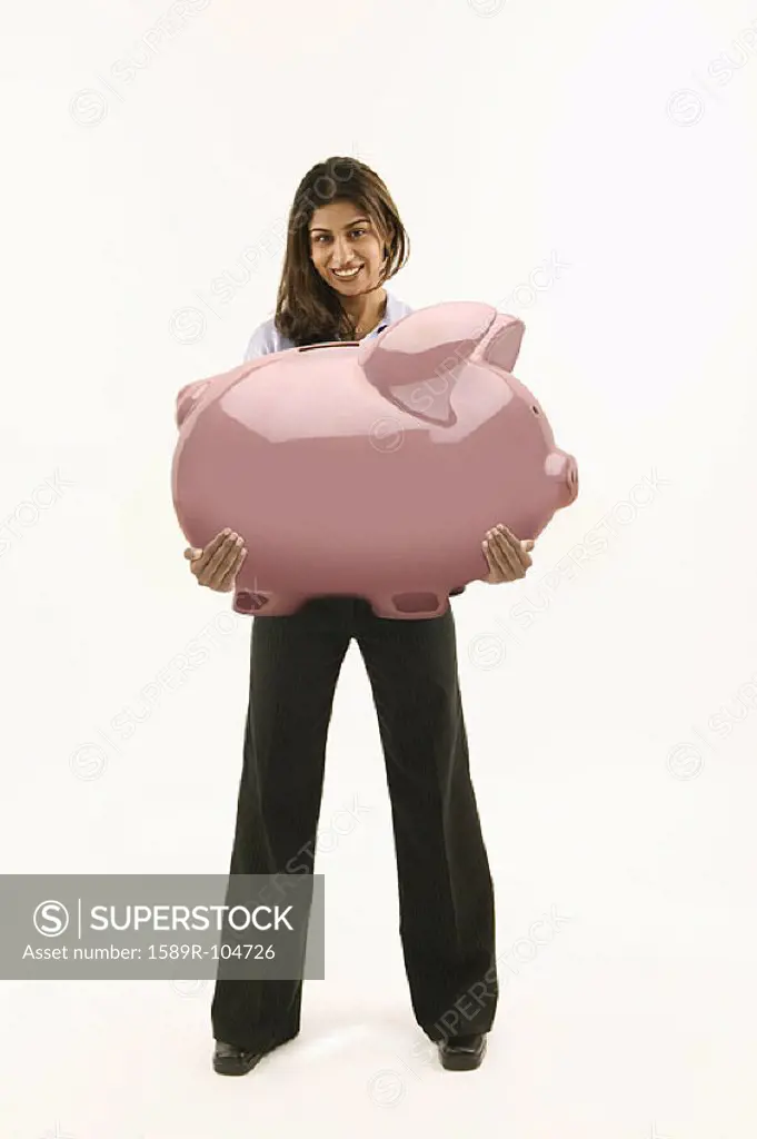 Young woman holding large piggy bank