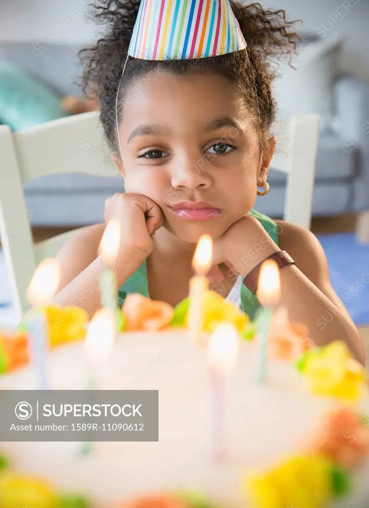 African American girl pouting at birthday cake