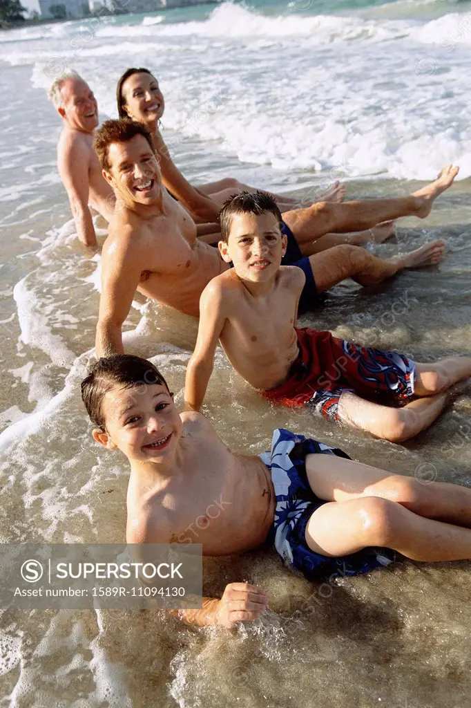 Family sitting in waves on beach