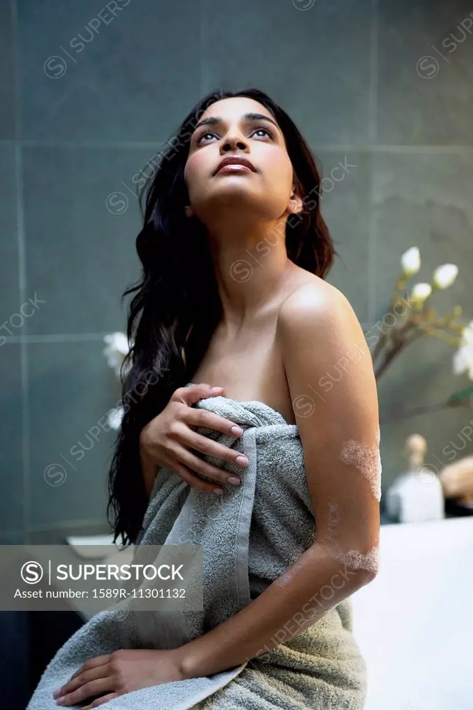 Hispanic woman wrapped in towel in bathroom