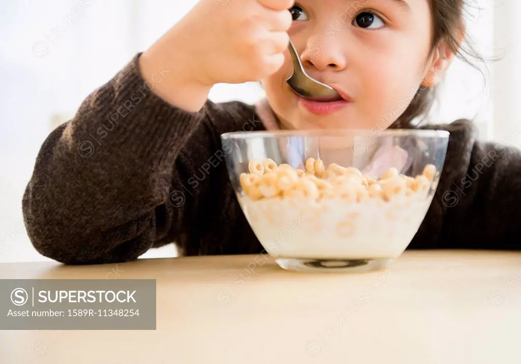 Hispanic girl eating bowl of cereal