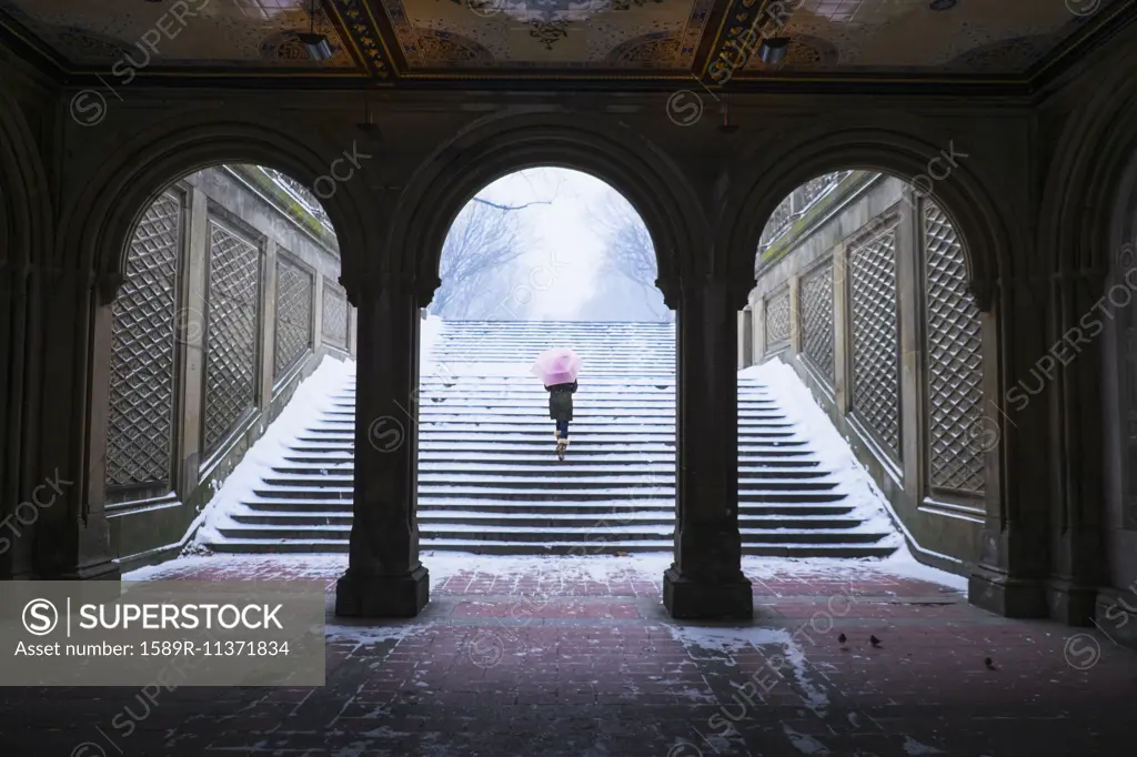 Asian woman walking up steps into snow