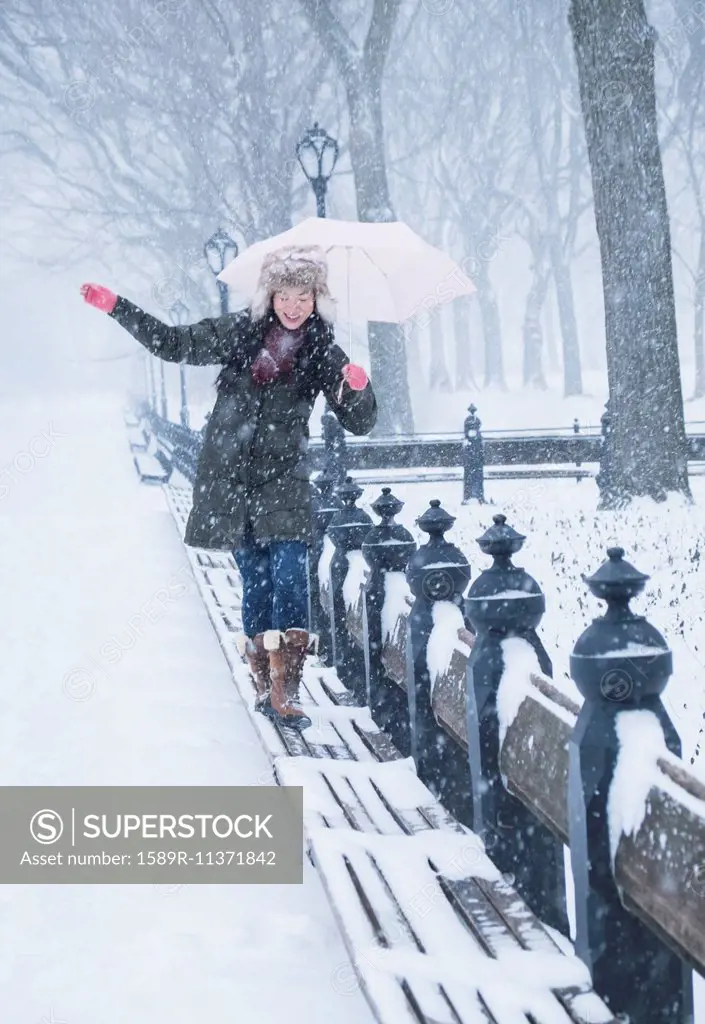 Asian woman walking on benches in snowy Central Park, New York City, New York, United States