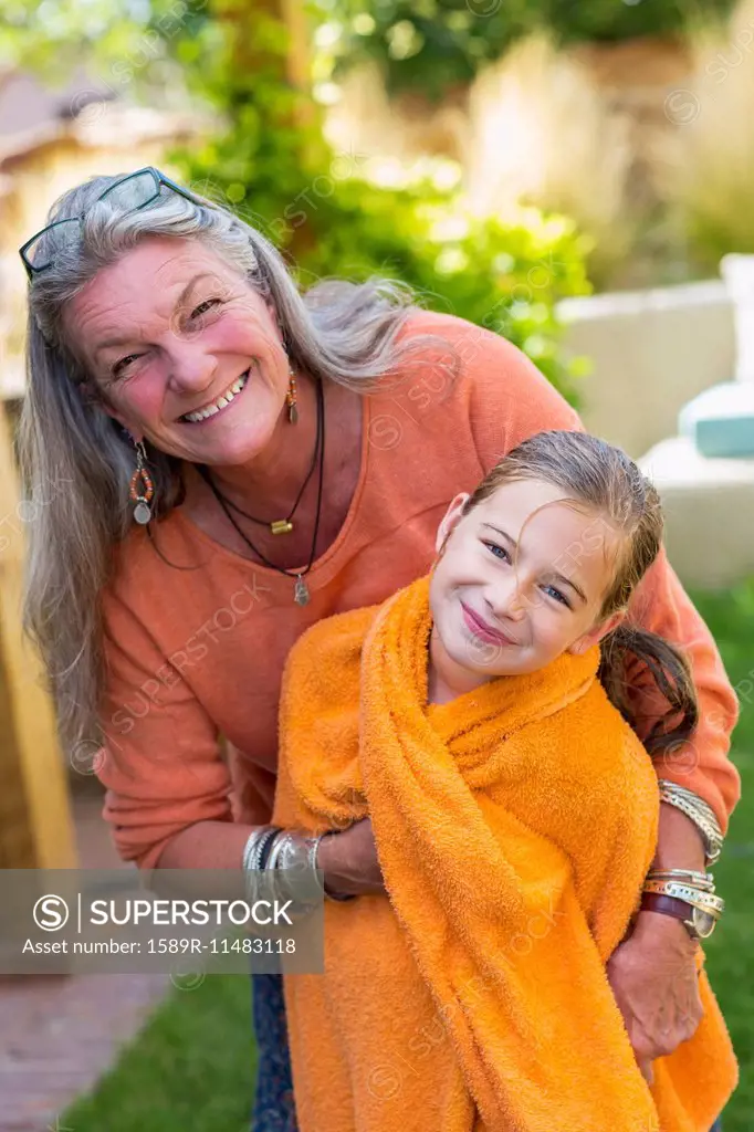 Caucasian grandmother wrapping granddaughter in towel in backyard