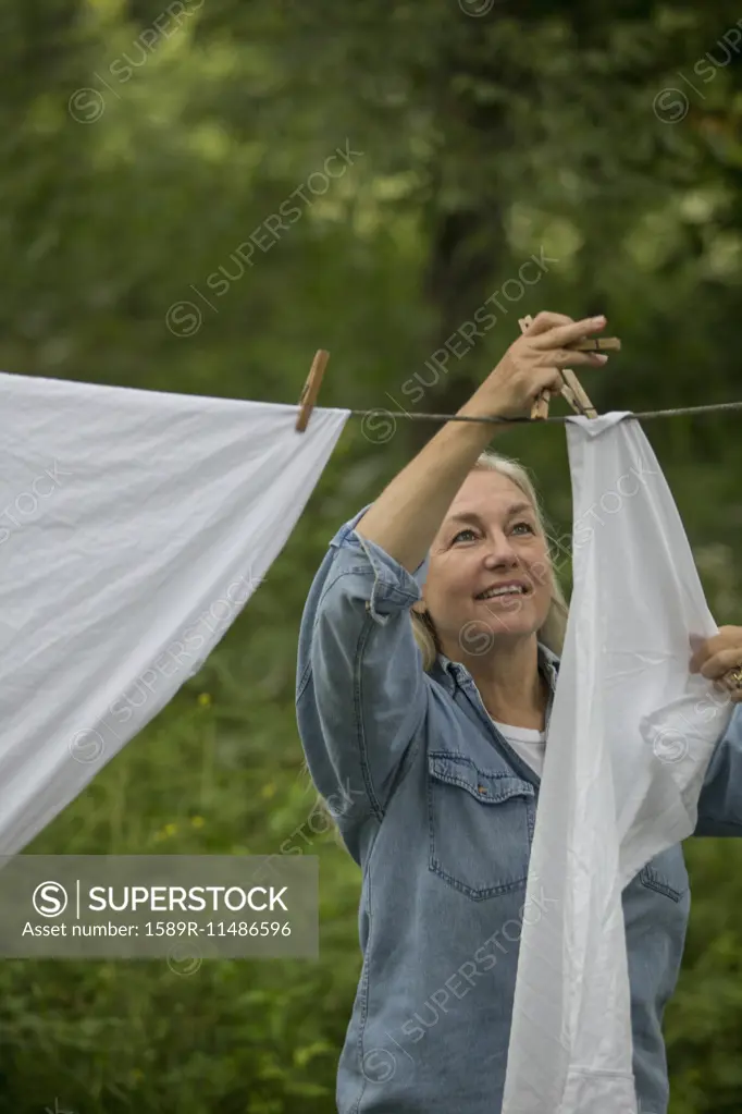 Older Caucasian woman hanging laundry on clothesline