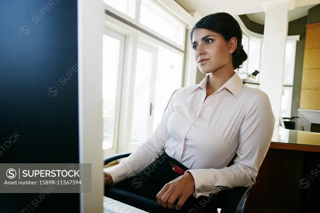 Mixed race businesswoman working at computer in office