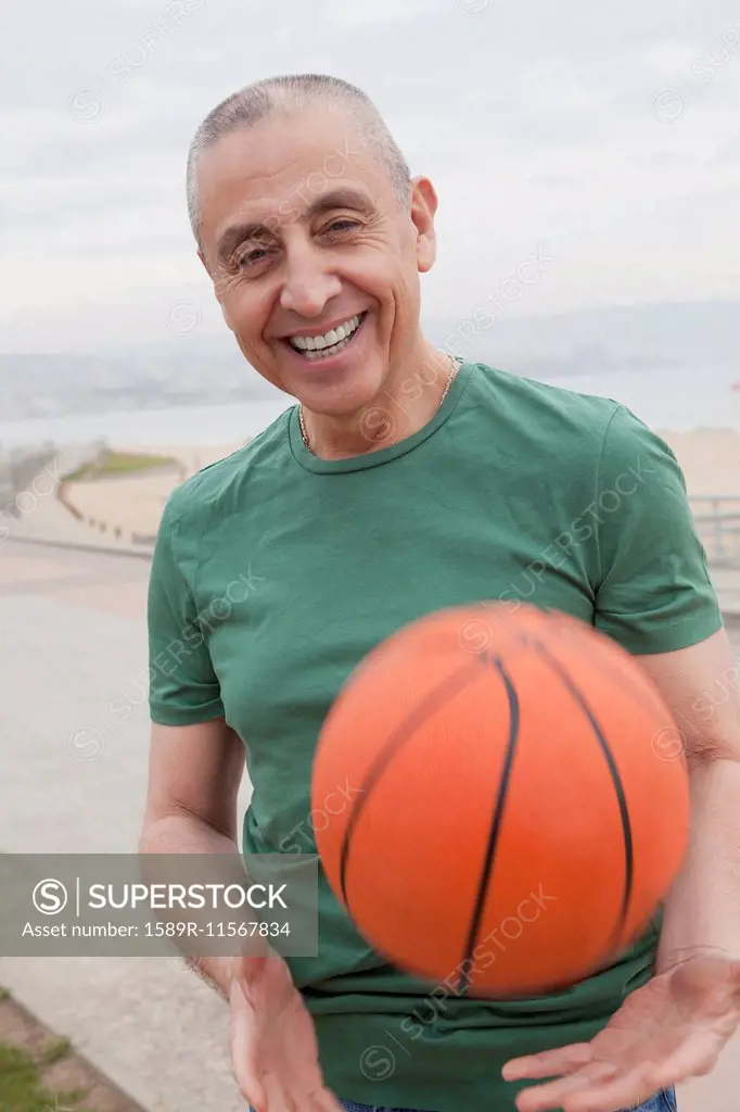 Hispanic senior man playing basketball outdoors