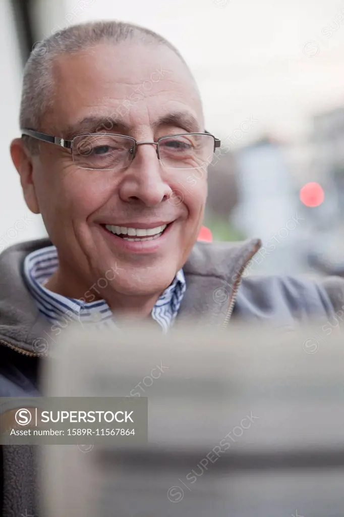 Hispanic senior man reading newspaper