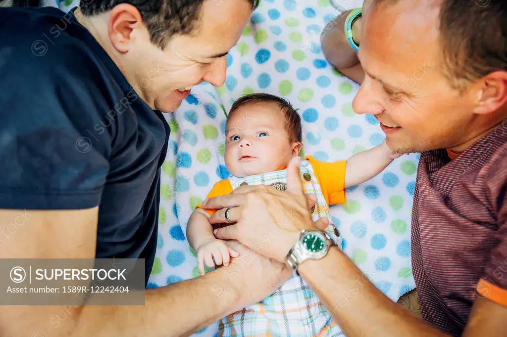 Caucasian gay couple cuddling baby boy