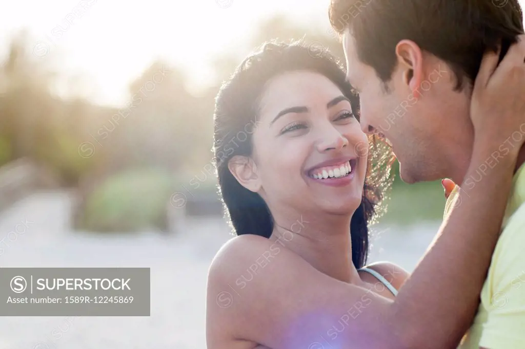 Hispanic couple embracing on beach