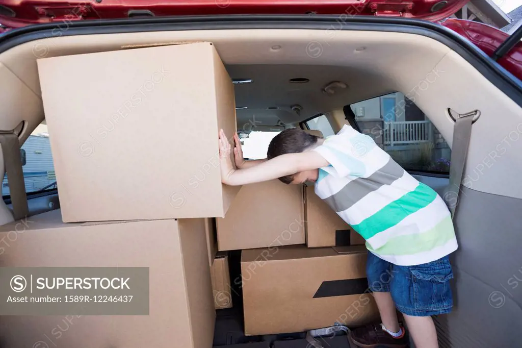 Caucasian boy packing cardboard boxes in car