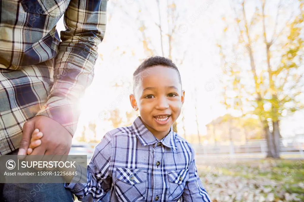 Black father and son walking in autumn leaves