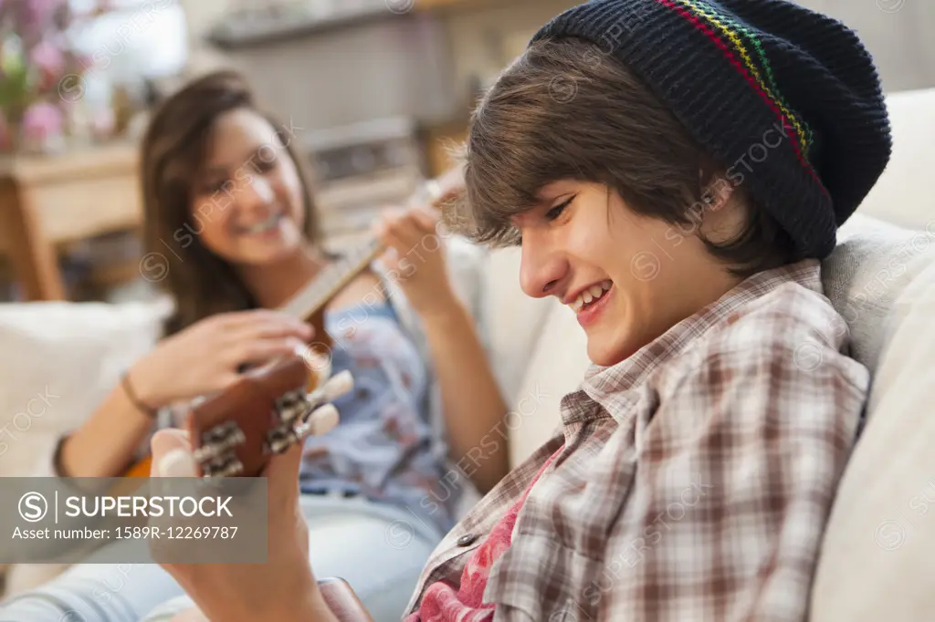 Mixed race friends playing ukuleles on sofa