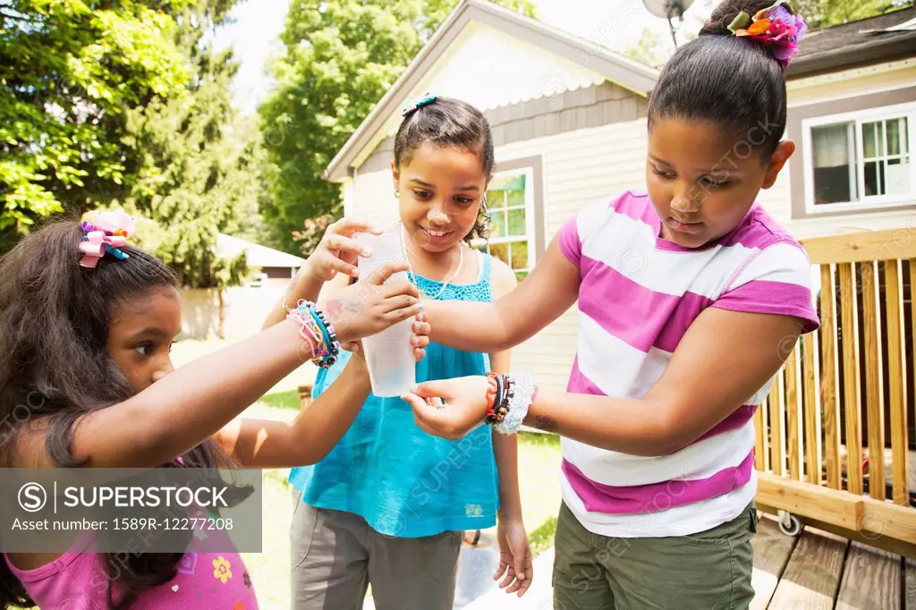 Hispanic girls examining water bottle