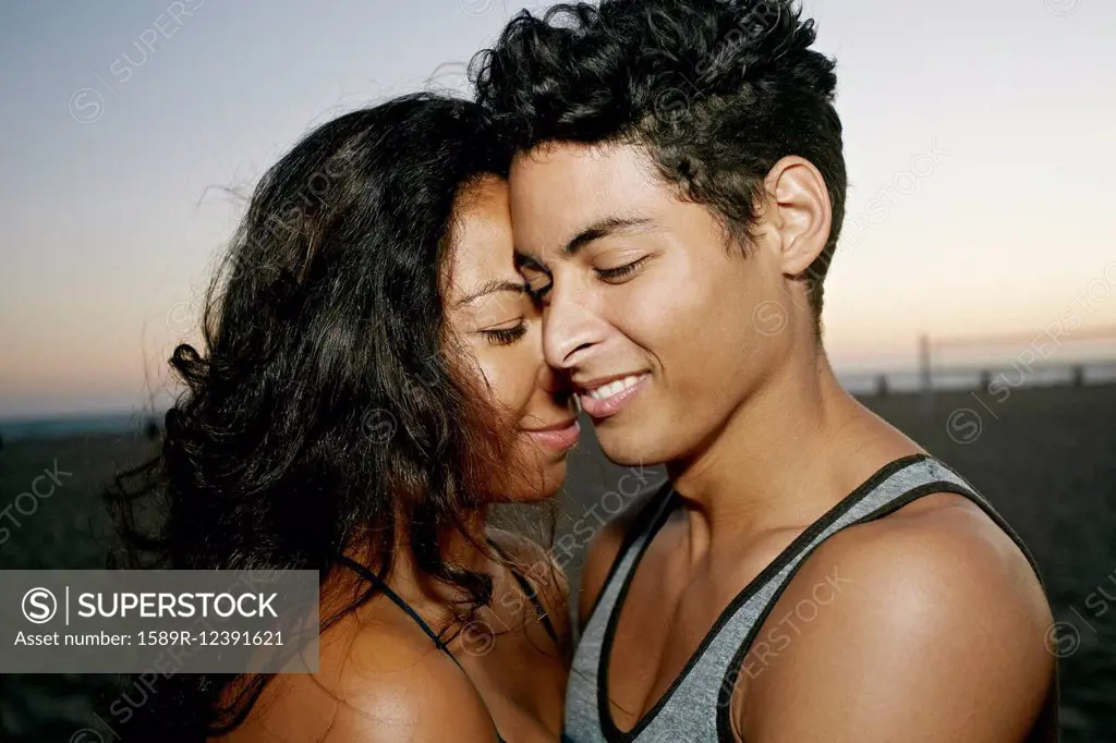 Hispanic couple hugging on beach