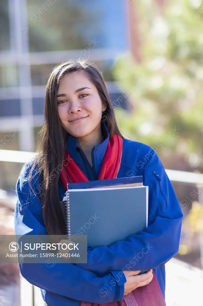 Mixed race student holding books on campus