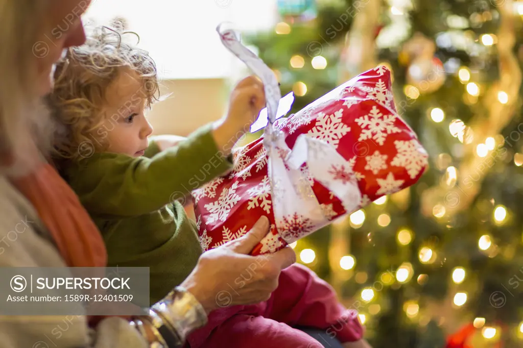 Caucasian grandmother and grandson opening presents near Christmas tree