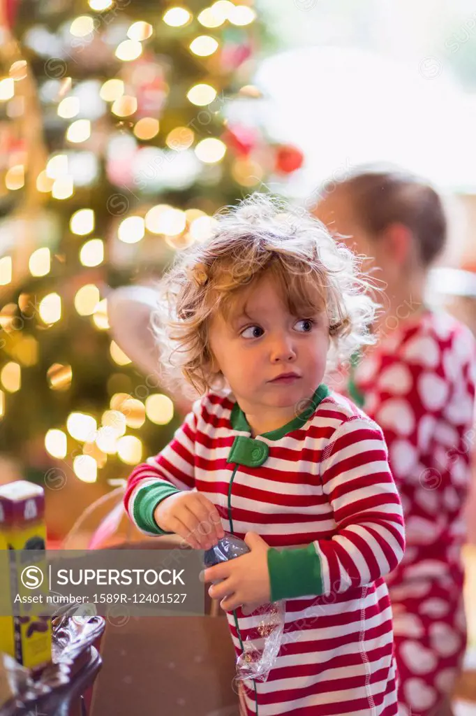 Caucasian baby boy opening present near Christmas tree