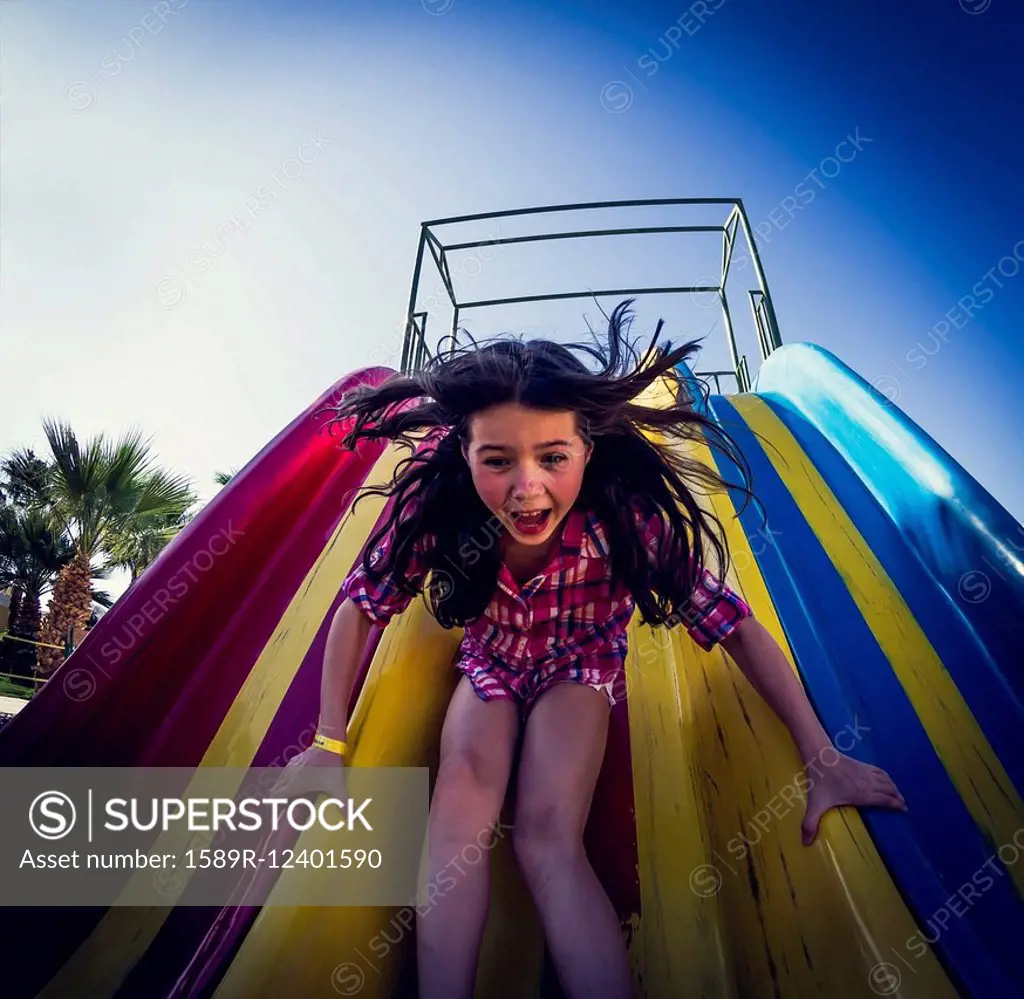 Caucasian girl playing on slide