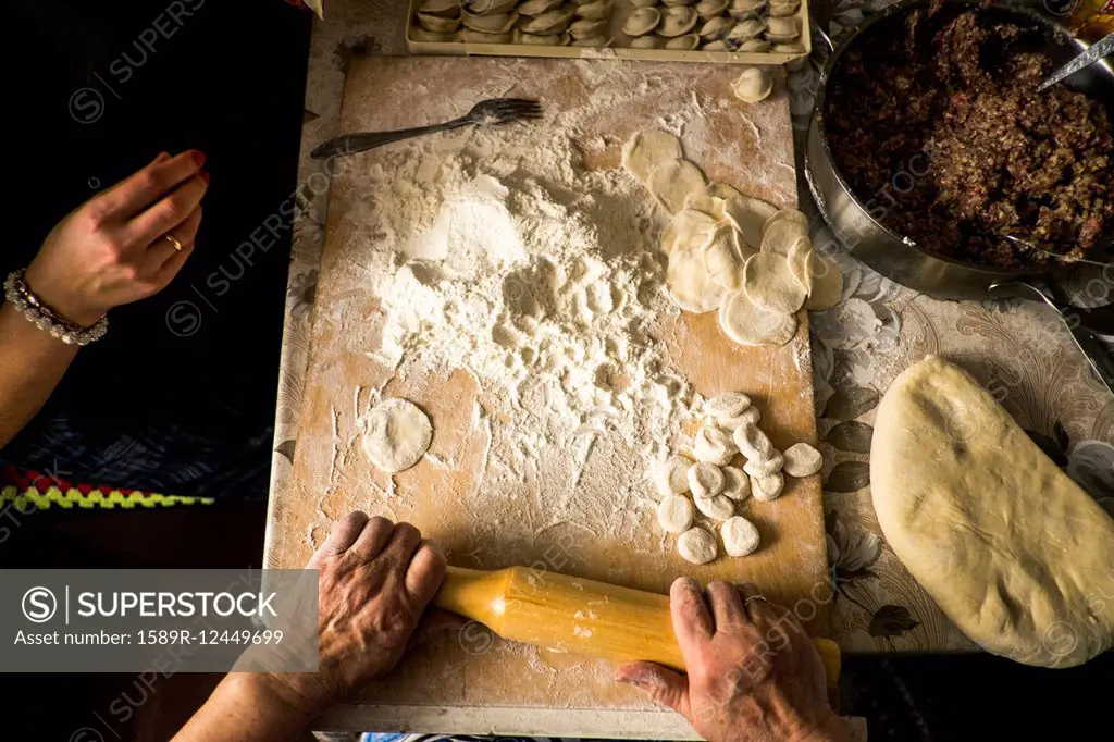 High angle view of family rolling pastry dough at kitchen table