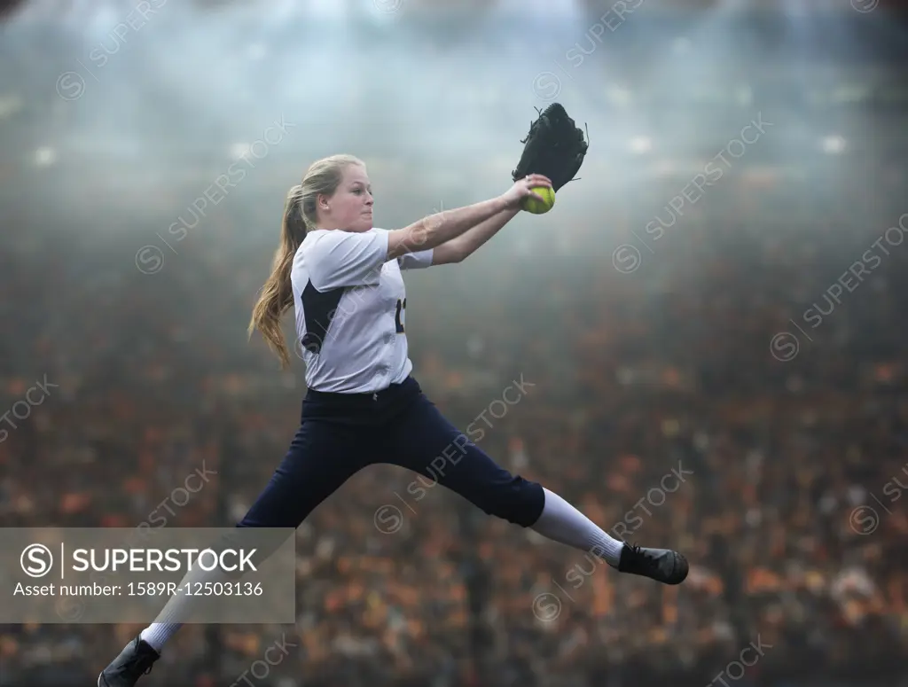 Caucasian softball player pitching ball in stadium