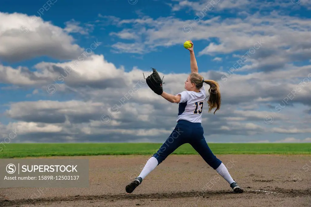 Caucasian softball player pitching ball in field