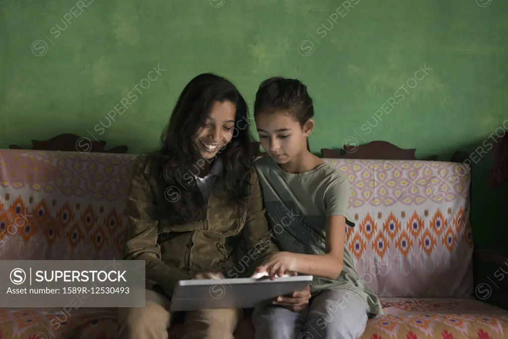 Aunt and niece using digital tablet on sofa