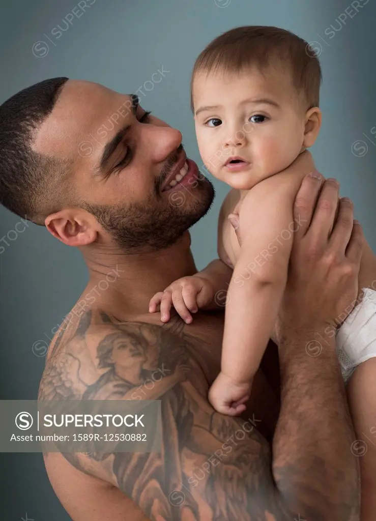 Father with tattoos holding baby son