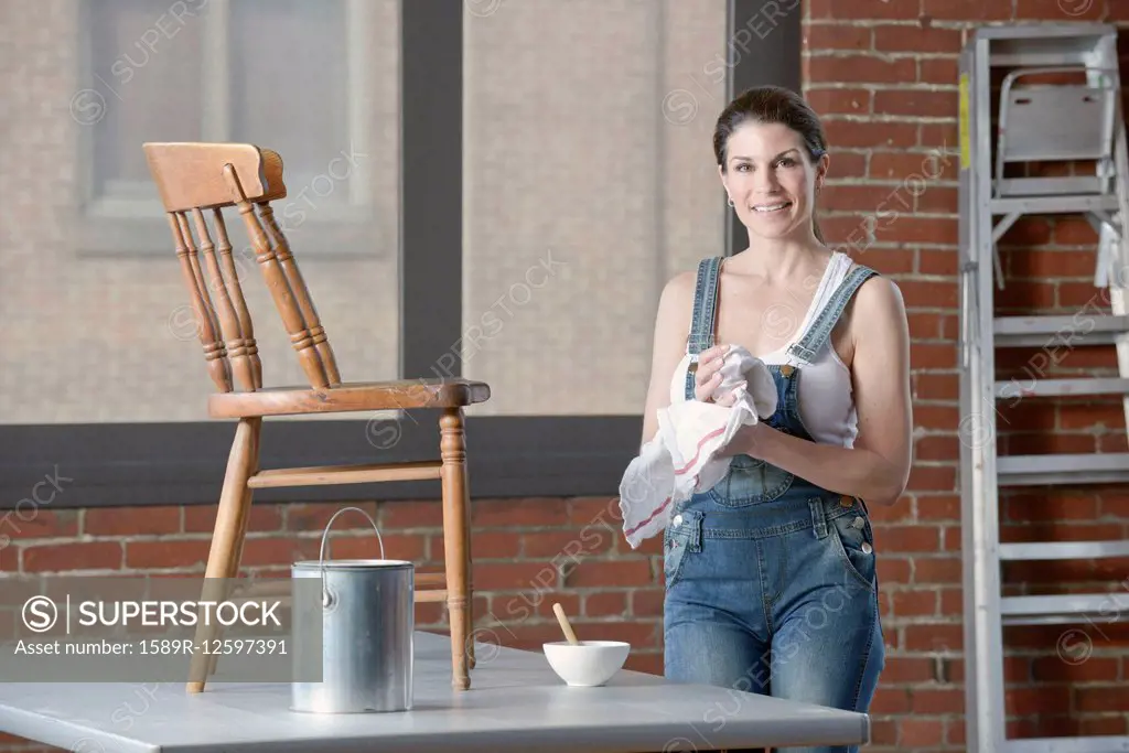 Mixed race woman painting chair in loft