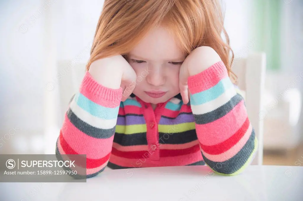 Caucasian girl crying at table