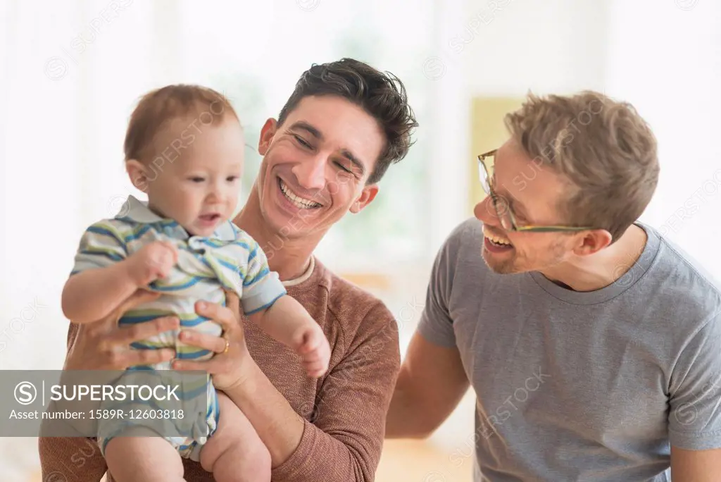 Caucasian gay fathers holding baby