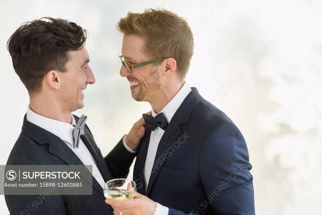 Caucasian gay grooms hugging at wedding