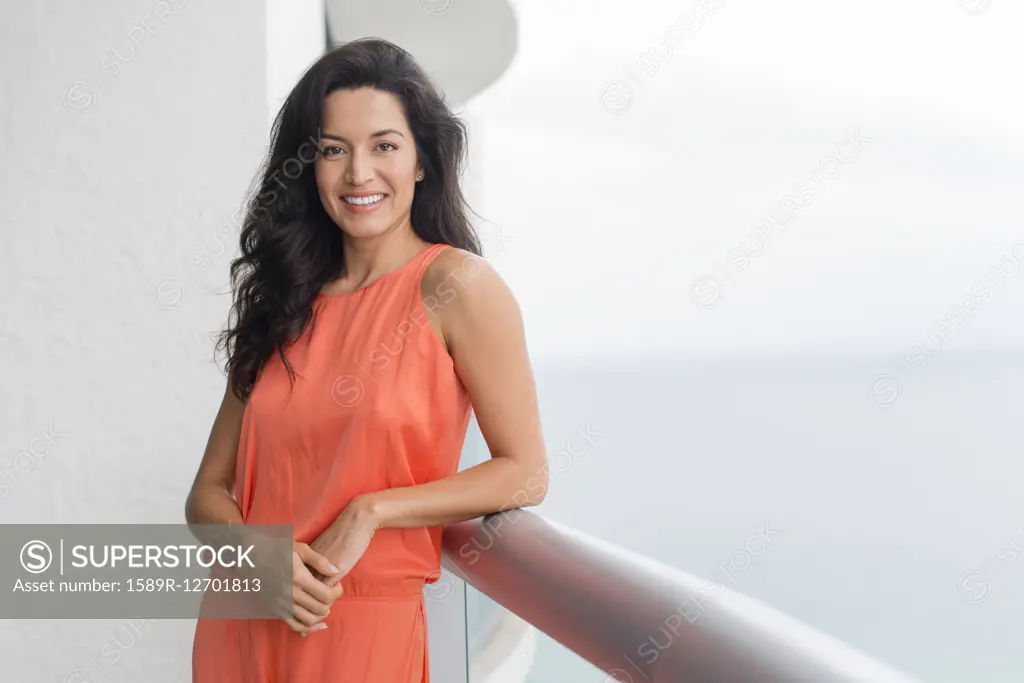 Hispanic woman leaning on balcony