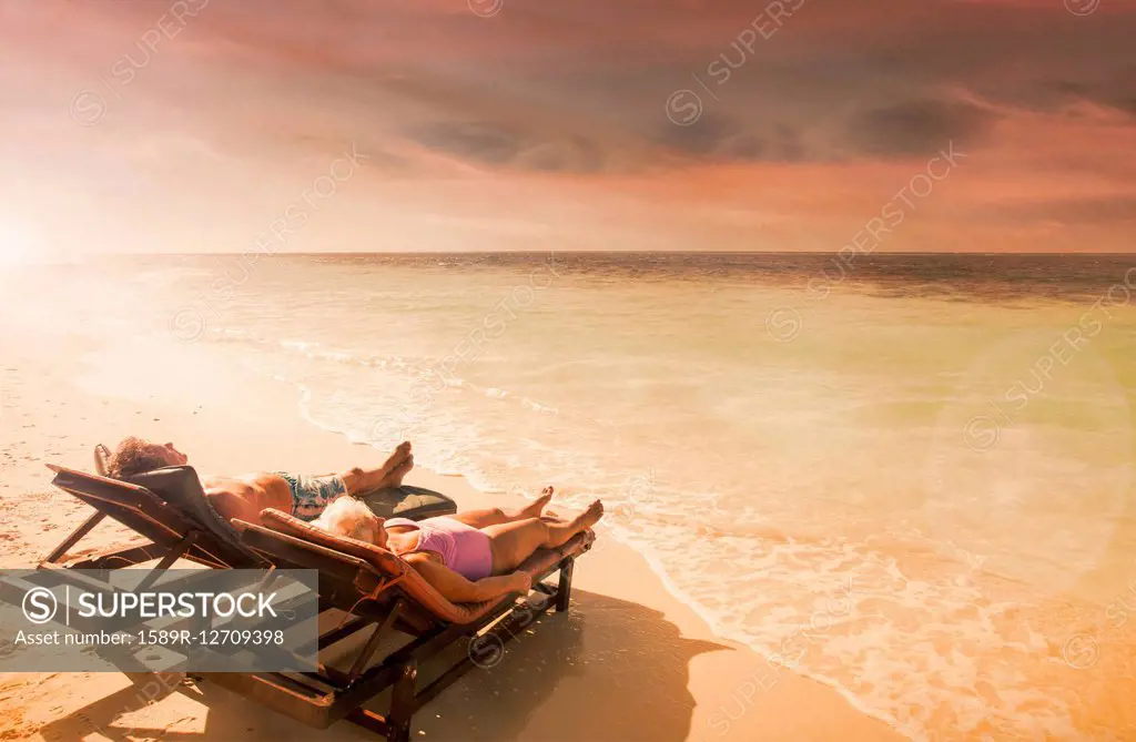 Older Caucasian couple relaxing on beach at sunset