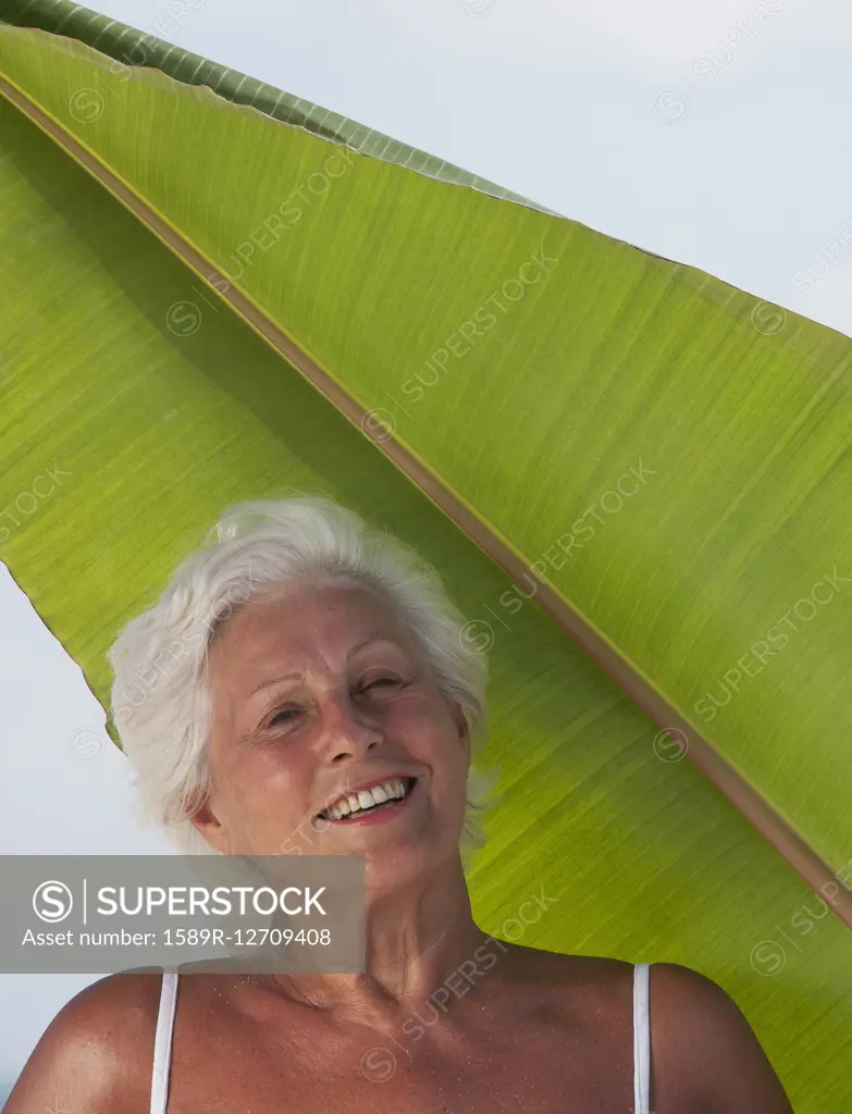 Older Caucasian woman standing under leaf